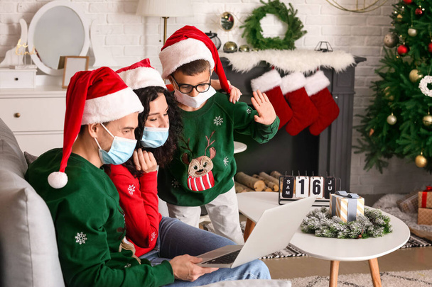 Familia con portátil que celebra la Navidad en casa debido a la epidemia de coronavirus - Foto, Imagen