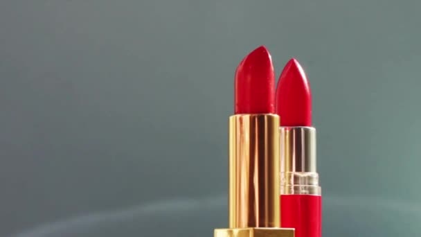 Dvě luxusní červené rtěnky na barevném pozadí a zářící světelné erupce, luxusní make-up a rekreační kosmetika pro značku beauty - Záběry, video