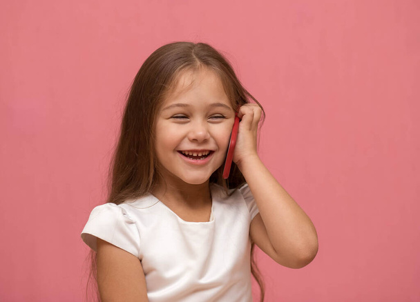 klein meisje spreekt aan de telefoon en lacht - Foto, afbeelding