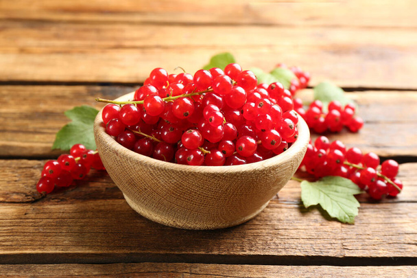 Ripe red currants in bowl on wooden table - Fotoğraf, Görsel