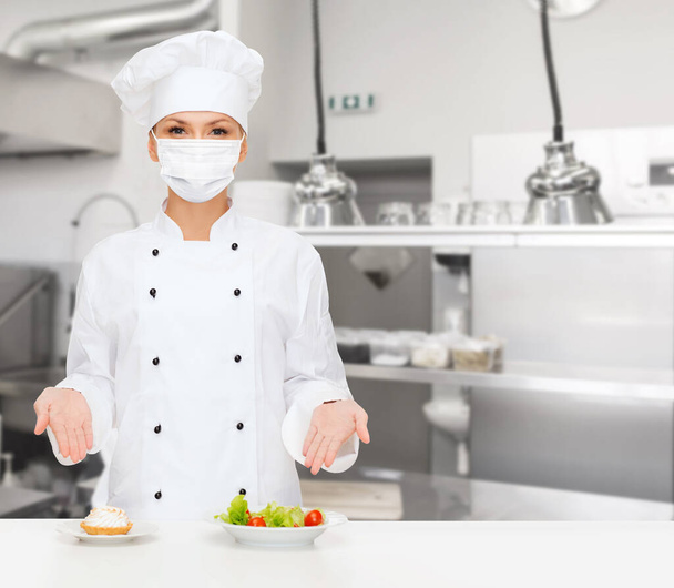 female chef in mask showing food at kitchen - Фото, зображення