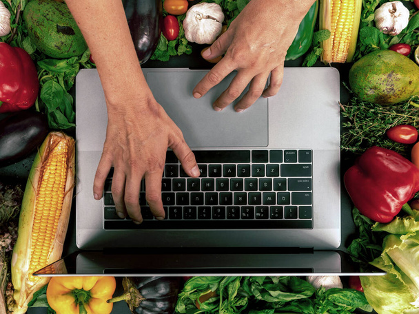 Online food ordering. Vegetables, laptop, hands. - Foto, imagen