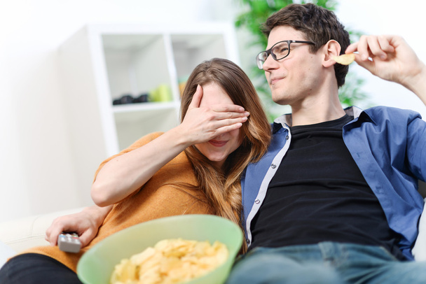 Pretty lovers eating and watching an horror or violent movie - Фото, изображение