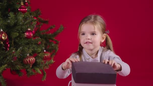 Milagro de Navidad. Feliz niña abriendo regalo de Navidad con luz mágica en el interior - Imágenes, Vídeo