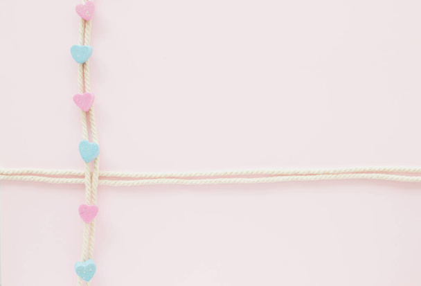Розовые мини-сердца на белой веревке, рождественские украшения на пастельном фоне - Фото, изображение