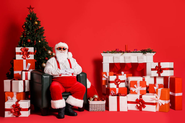 Portrait of his he attractive funky fat overweight cheery glad Santa father sitting in armchair in decorated living-room festal spirit isolated bright vivid shine vibrant red color background - Photo, image