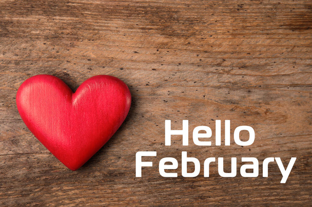 Greeting card with text Hello February. Red decorative heart on wooden background, top view - Foto, afbeelding