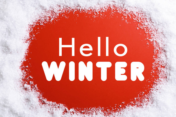 Cartão de felicitações. Neve em torno do texto Olá Inverno no fundo vermelho, vista superior - Foto, Imagem