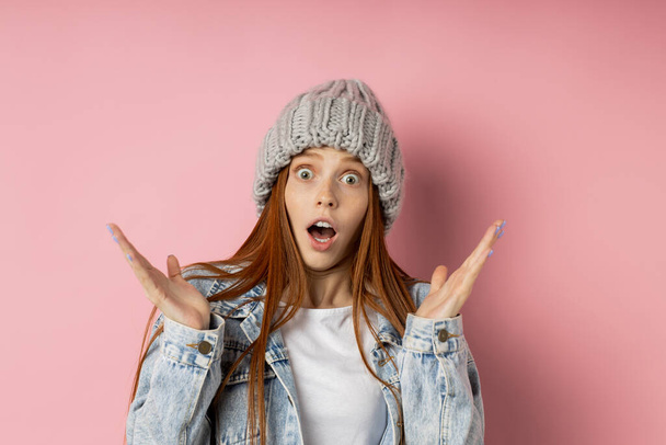 Portrait of excited young woman dressed denim jacket and knitted hat - Фото, изображение