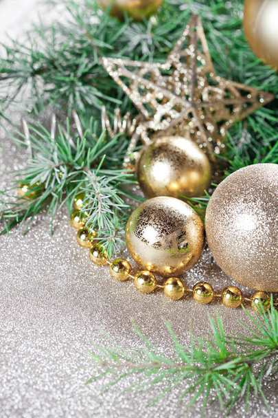 Christmas decorations and evergreen fir tree branch closeup on gold glitter background. - Fotó, kép