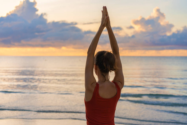 Spor kıyafetleri giyen çekici genç bir kadın tek başına yoga yapıyor. Yogi dişisi deniz kenarında esniyor ve egzersiz yapıyor. Uzayı kopyala, arkaplan. Zen kavramına ulaşılıyor. - Fotoğraf, Görsel
