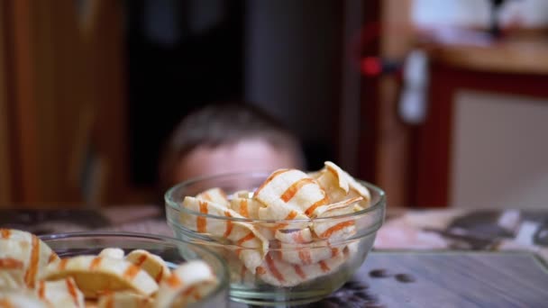 Hongerige tiener steelt chips van tafel in een plaat, terwijl niemand ziet - Video