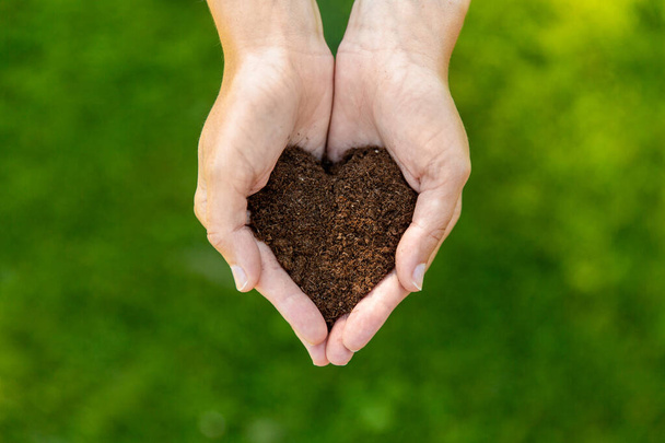 cupped hands holding soil in shape of heart - Фото, зображення