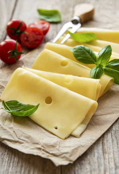 Eski ahşap bir masada dilimlenmiş peynir, fesleğen ve domates. - Fotoğraf, Görsel