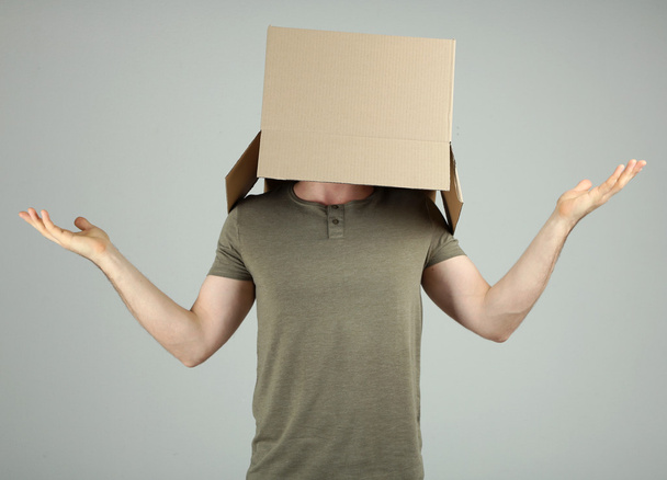 Man with cardboard box on his head on grey background - Foto, imagen