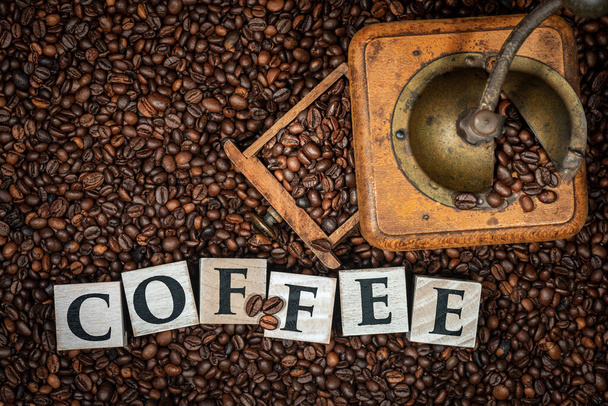 焙煎したコーヒー豆と木のブロックで作られたテキストコーヒーと古い手動コーヒーグラインダーのトップビュー. - 写真・画像