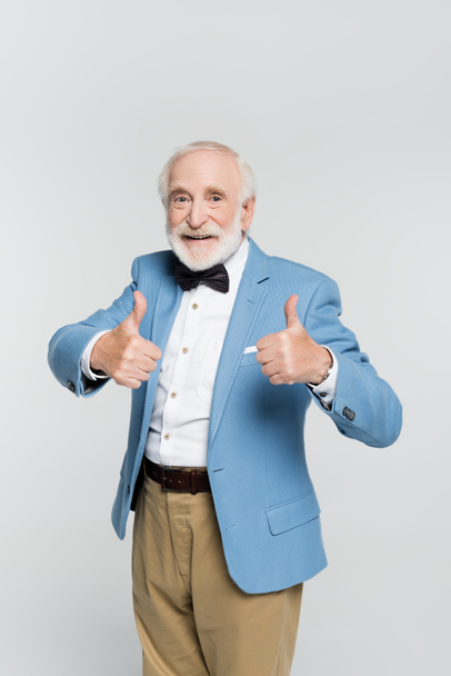 Positive senior man showing like gesture and looking at camera isolated on grey  - Foto, Imagen