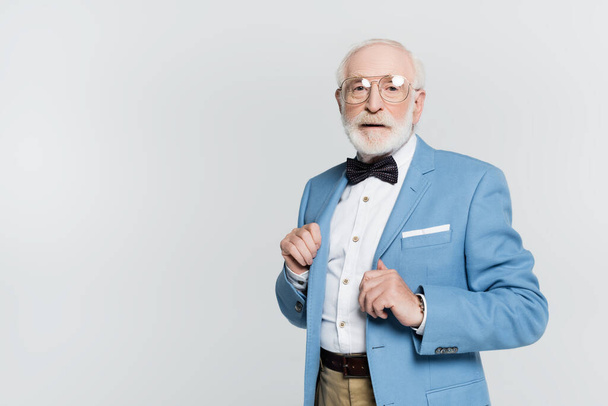Senior man in jacket and bow tie looking at camera isolated on grey  - Фото, изображение