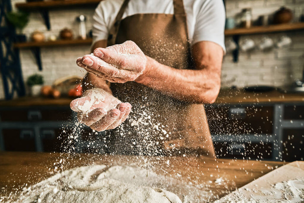 Close up of male hands sprinkling dough with flour while cooking on the kitchen. Baking process concept - Φωτογραφία, εικόνα