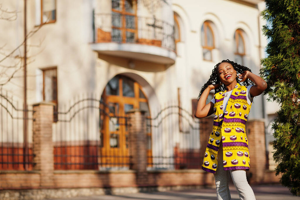 Stylish african american women in yellow jacket posed on street at sunny day. - Фото, зображення