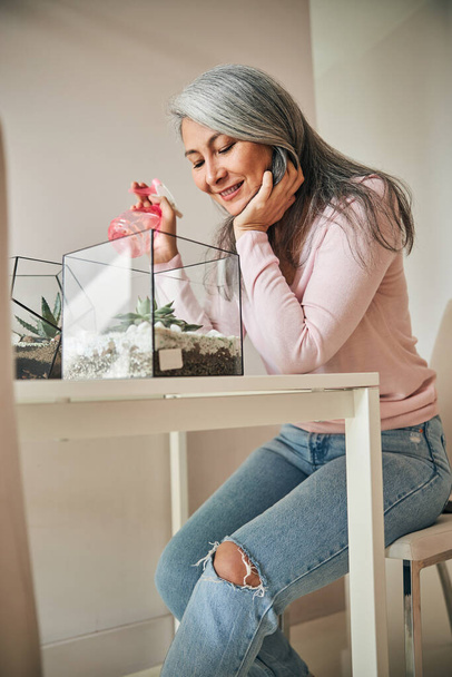Радостная женщина ухаживает за сочными растениями дома - Фото, изображение