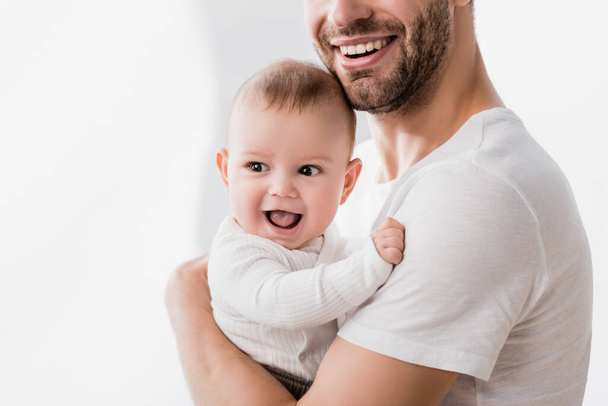 happy father holding in arms excited baby boy with open mouth - Photo, image