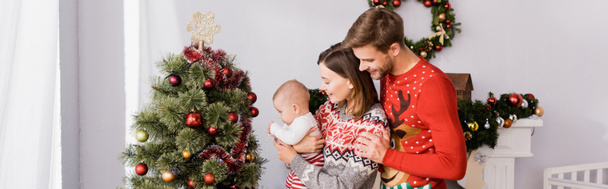 Mutlu bir kadın kucağında kollarıyla neşeli bir koca ve süslü bir Noel ağacı taşıyan bir oğlan çocuğu, afiş - Fotoğraf, Görsel
