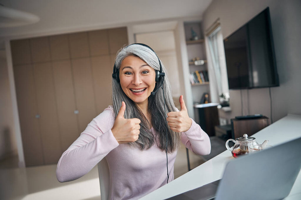 Iloinen nainen käyttää kannettavaa tietokonetta ja antaa peukalot ylös - Valokuva, kuva