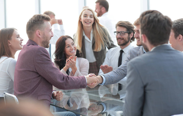 smiling business partners shaking hands, to the applause of the business team - Foto, Imagen