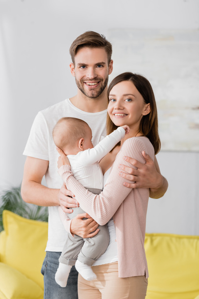 happy woman holding in arms baby boy near cheerful husband  - Foto, imagen