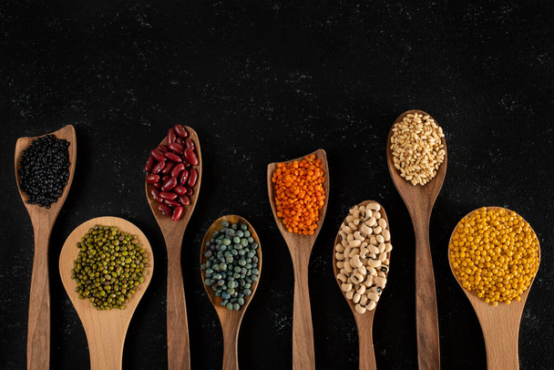 Various of organic legumes on the wooden table. Dried peas and legumes concept in the bowl and in the spoon.  - Photo, Image