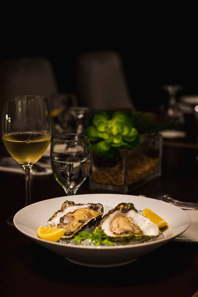 two raw fresh oysters served on a bed of ice with two wedges of lemon - Foto, immagini