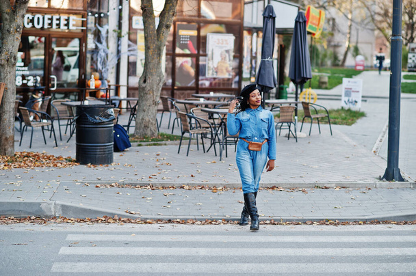 Stylish fashionable african american women in jeans wear and black beret walking on pedestrian traffic. - Fotó, kép