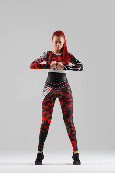Pretty girl with red hair in tight sportswear isolated on gray background. - Fotoğraf, Görsel