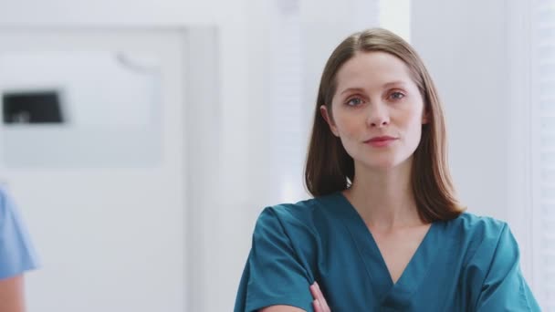 Portrait of female doctor wearing scrubs being passed by male colleague in hospital corridor - shot in slow motion - Séquence, vidéo