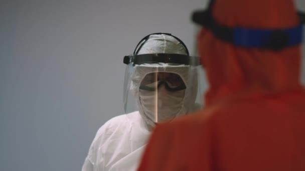 Врачи в защитных костюмах консультируются со статусом коронавируса - Кадры, видео