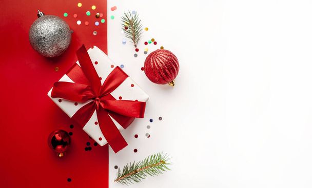 Weihnachtskomposition auf weißem Hintergrund mit weißem Geschenkkarton, mit rotem Band mit Tannenzweigen, Spielzeug, Kopierraum für Ihre Glückwünsche - Foto, Bild