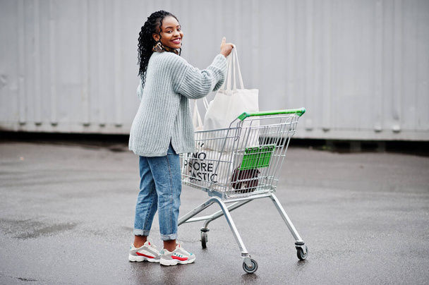 Nincs több műanyag. Afrikai nő bevásárlókocsi kocsi és ökotáskák pózolt szabadtéri piacon. - Fotó, kép