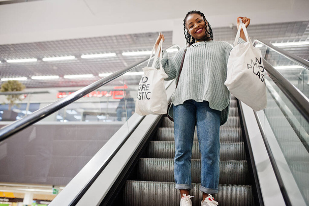African woman with shopping eco bags on escalator at mall. - Fotó, kép