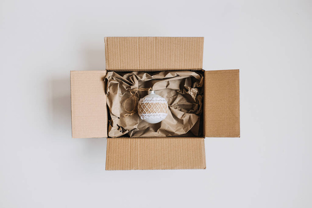 Budget christmas gifts, Cheap Christmas presents, Inexpensive Xmas. Gift Ideas for a Tight Christmas Budget. Cardboard box with packaging kraft paper and one gift - Фото, зображення