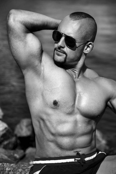 Black and white portrait of a sexy athletic male with a naked torso, outside. - Zdjęcie, obraz