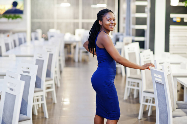 Charming african american woman in blue dress posing at restaurant. - 写真・画像