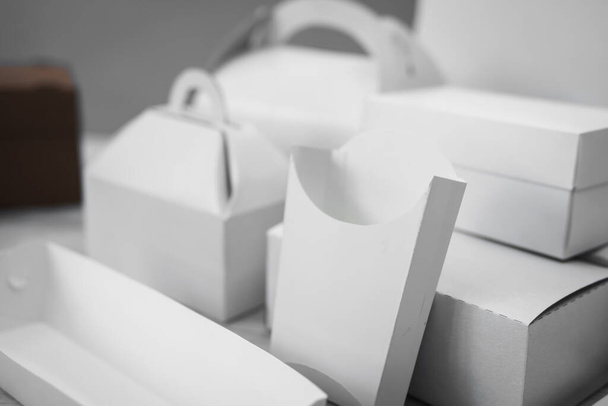 Different types of white cardboard packaging. For fast food, folding, large and small. The concept of production and design of paper products. Place for text. Selective focus. copy space - Fotó, kép