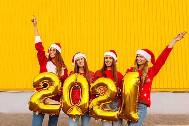 Group of cheerful young women in santa claus hats with balloons 2021 new year celebration - Fotografie, Obrázek