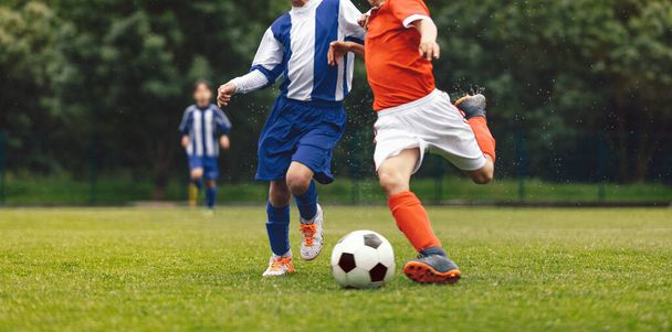 Tinédzser fiúk a foci klubokban versenyeznek a bajnokságon. Focimeccs iskolásoknak. Foci mez sportruházatot viselő játékosok, akik füves pályán futnak és focilabdáznak. Junior foci játék - Fotó, kép
