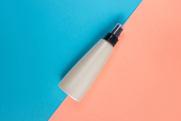 Bottle for liquid, cream, gel, lotion. osmetic bottle on blue and rose background. SPA cosmetic product branding mockup. Flat lay minimalist style. - Φωτογραφία, εικόνα