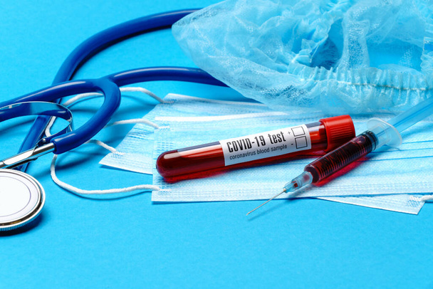 Medical lab concept - Covid-19 blood sample in test tube and syringe on blue background - Fotoğraf, Görsel