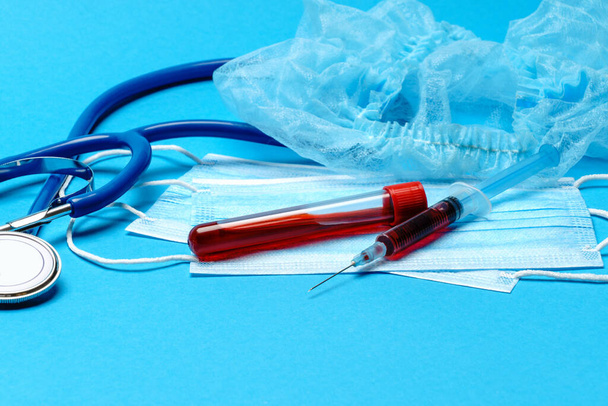 Medical lab concept - Covid-19 blood sample in test tube and syringe on blue background - Фото, изображение