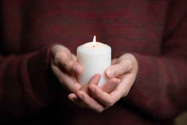 A man holding a candle in front of his chest - Photo, image