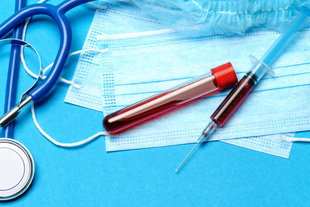 Medical lab concept - Covid-19 blood sample in test tube and syringe on blue background - Zdjęcie, obraz